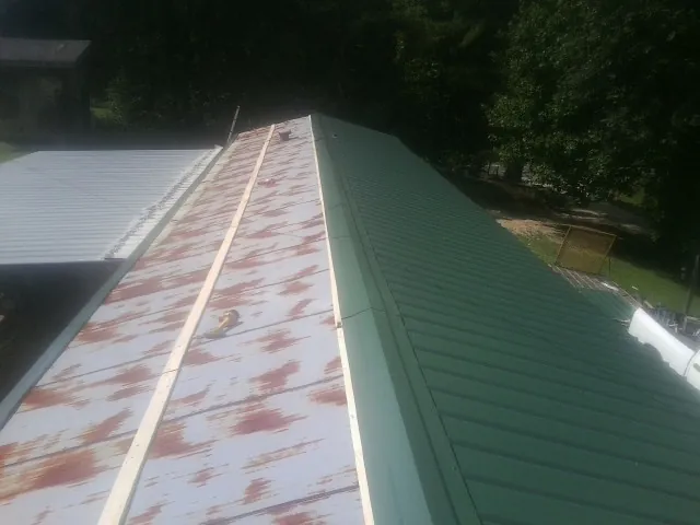 Old rusted panels beside newly installed green metal roofing — Wind Damage Roof Repair by Roofing Brothers in Parlin