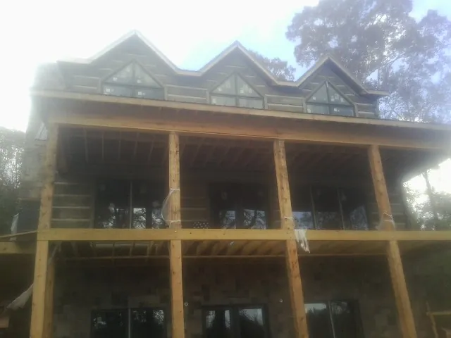 Dormers and porch framing on a large log home under construction — Roof Coating work by our crew in Parlin