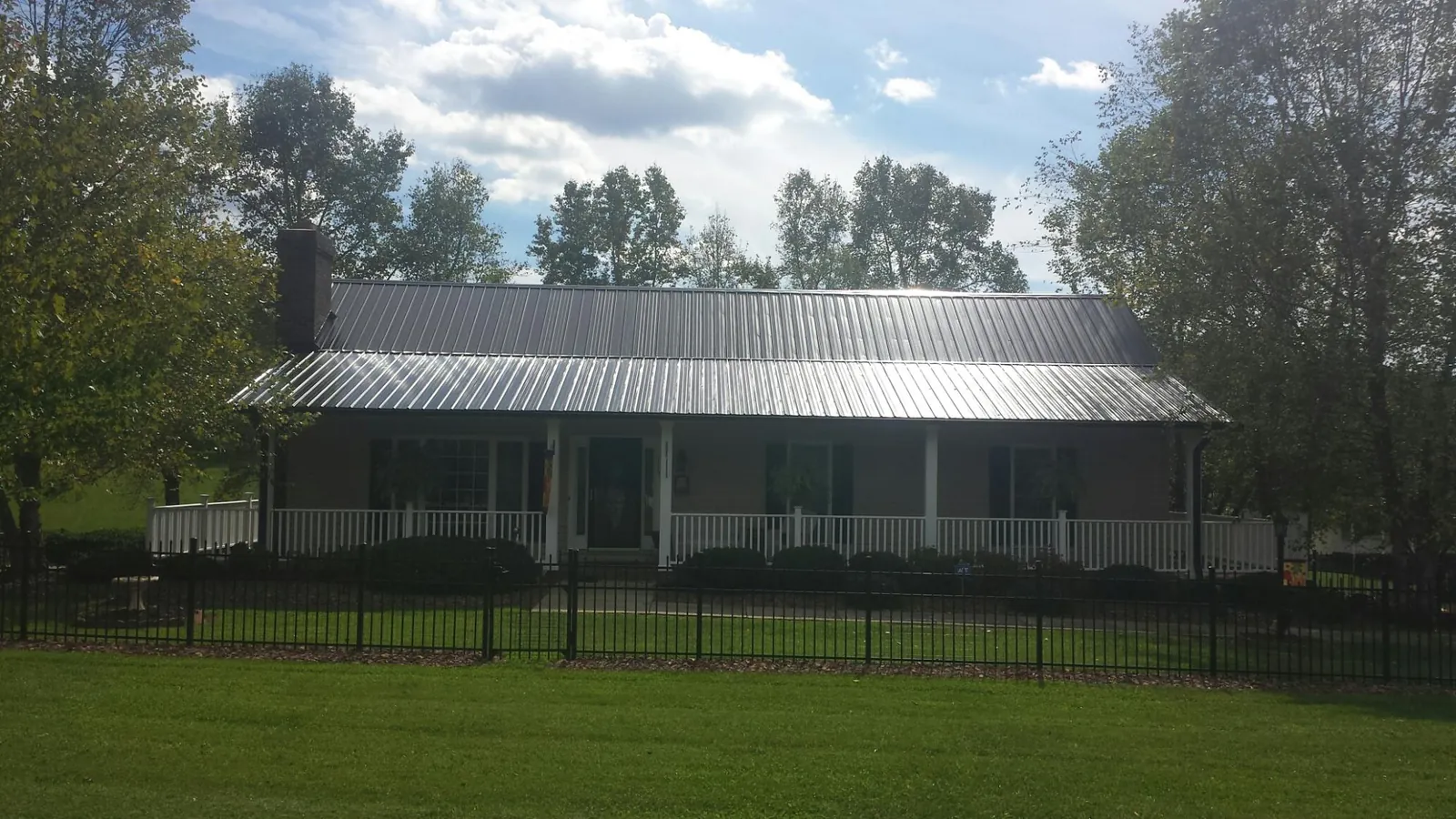 Gray metal roof on a brick ranch with a full width front porch — Gutter Guard Installation work by our crew in Parlin