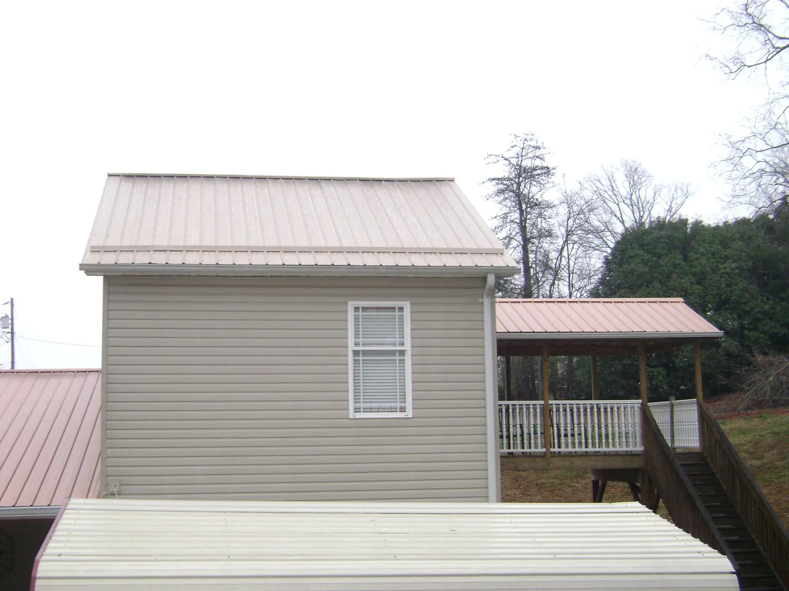Tan metal roofs on a two story addition and attached porch, from a Roof Replacement job in Parlin