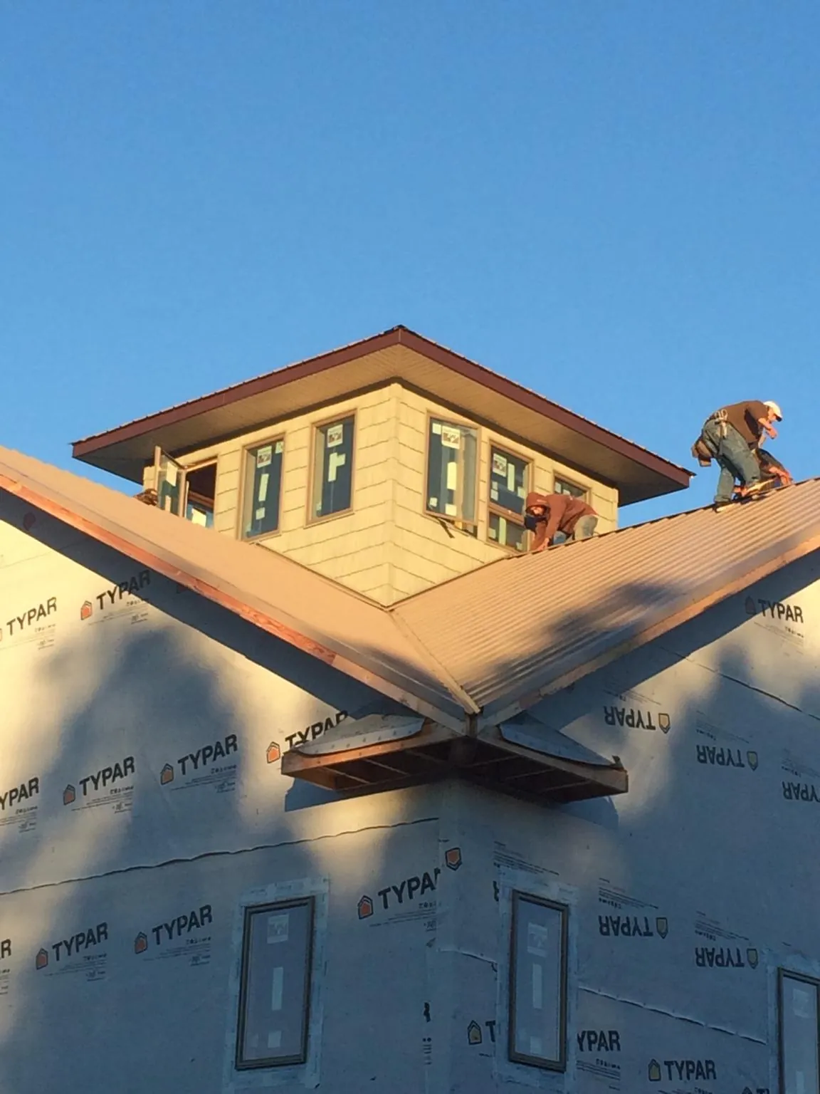 Roofers working around a rooftop cupola on a new metal roof at sunset — Roof Waterproofing in Parlin by Roofing Brothers